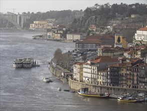 A river landscape with boats, historic houses and a bridge in the background creating a picturesque