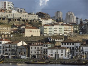 City view with buildings stretching up the hill, along a river under a cloudy sky, old houses in