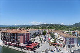 Market square with shops and restaurants, in the background the hills of the Massif des Maures,
