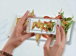 Woman takes a photo of her food with her mobile phone