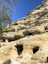 View upwards to sandstone rocks at the edge of Matala bay with entrances to caves of former Roman