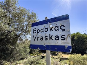 Bullet holes in town sign is target for target practice perforated by bullets, Crete, Greece,