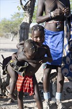 Two children wrestle, children of the Hakaona in the morning light, Angolan tribe, near Opuwo,