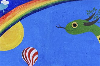 Colourful mural with a snake, sun, rainbow and a hot air balloon under a clear sky, mural, East