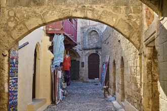 Narrow cobbled street with arches and lined up towels in an old part of town, Old Town of Rhodes,
