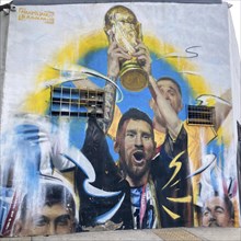 Street art mural by Maximiliano Bagnasco shows triumphant Lionel Messi with the World Cup trophy,