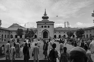 Black and white image of people in the courtyard of a large mosque with historical architecture,