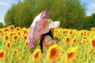 Young woman with a parasol in a field of sunflowers