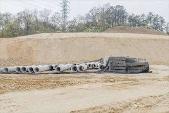 Concrete culvert pipes at base of dirt hillside at rural construction site in Daejeon, South Korea,