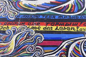 Colourful graffiti waves with texts in different languages on a wall, mural, East Side Gallery,