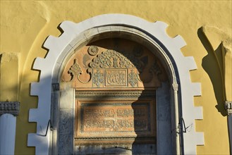 Ottoman library, detail of a historic archway with inscriptions and ornaments, above a yellow wall