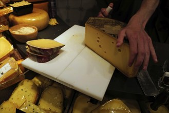 Dutch cheese being cut using a wire cheese slicer. Amsterdam, Netherlands