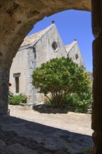 View through archway to rear wall of two-nave church building Church of Arkadi Monastery UNESCO