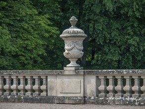 Stone sculpture in a well-kept garden, surrounded by a balustrade and green foliage in the