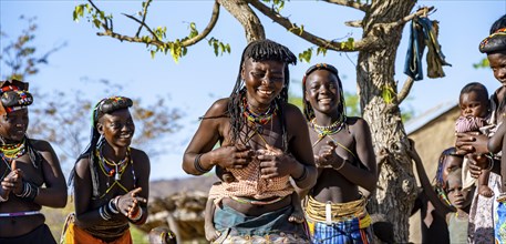 Hakaona woman with traditional kapapo hairstyle, dancing, clapping and laughing, Angolan tribe of