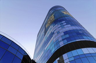 A modern skyscraper with a blue reflective glass facade and advertising, illuminated in daylight,