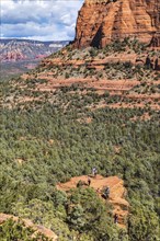 Hikers climb to the top of a red rock sandstone formation along the Devil's Bridge Trail in Sedona,