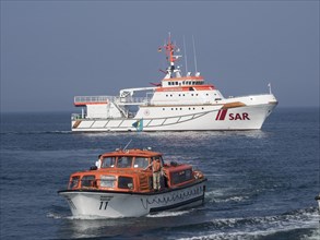 A rescue ship and a small boat in the sea in sunny weather, Heligoland, Germany, Europe