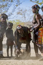 Hakaona woman with traditional kapapo hairstyle, drumming u, Angolan tribe of the Hakaona, near