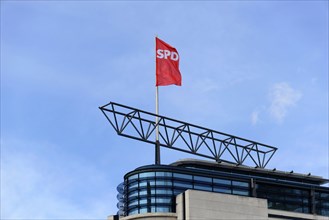 Red SPD flag flies on a modern building under a clear blue sky, Willy-Brandt-Haus, SPD