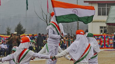 Children in white uniforms holding the Indian flag while participating in a parade filled with