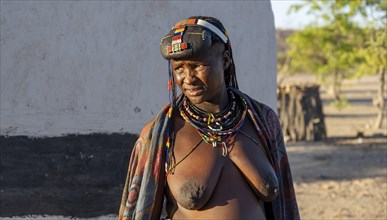 Hakaona woman with traditional kapapo hairstyle and colourful necklaces, in the morning light,