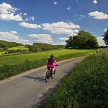 Cyclist in hilly landscape with blue sky and clouds, Wetter (Ruhr), Ruhr area, North