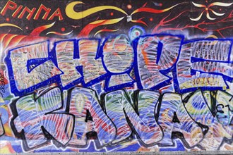 Mural with fiery designs and a large blue graffiti lettering in the foreground, overlaid with text,