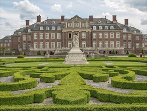 Historic castle with stone sculpture and well-kept hedge garden, old red brick castle with towers