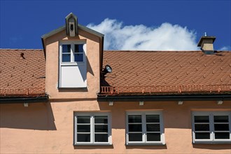 Red facade and tiled roof with crane dormer in the Muehlberg ensemble is a heritage-protected group