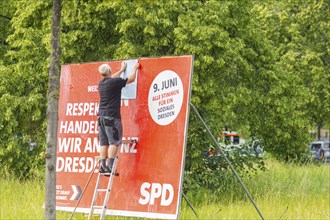 A poster artist renews a large SPD campaign poster for the elections on 8 June 2024, in the city