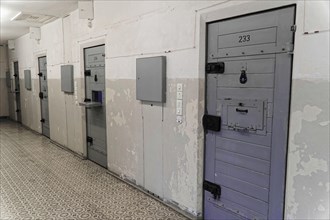 Corridor in a prison with worn grey metal doors and security area, Berlin-Hohenschoenhausen