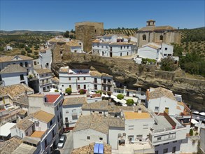 Aerial view of a Spanish village with white buildings, historic buildings, churches and olive