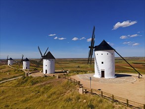 Grouped windmills on a hill under a bright blue sky in a vast summer landscape, aerial view,