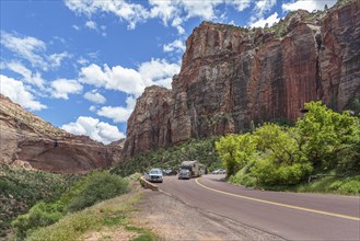 Recreational vehicle passes tourists at an overlook next to a blind arch along the Zion Park