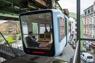 The suspension railway runs alongside colourful historic buildings in a German city, Wuppertal