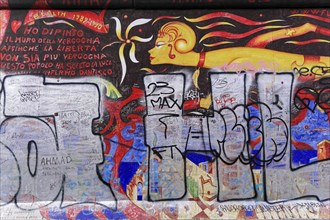 Colourful mural with a fiery female figure and Italian lettering, overlaid with large graffiti