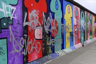 Long wall with colourful graffiti and inserted texts and symbols, mural, East Side Gallery,