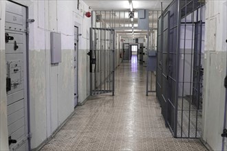 Long corridor of a prison with metal and barred doors and worn walls, Berlin-Hohenschoenhausen
