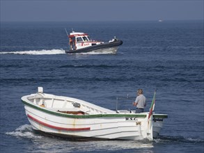 A white boat with a man and a SAR lifeboat at sea, Helgoland, Germany, Europe