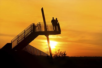 Pluto spoil tip viewing platform with a couple at atmospheric sunset, Herne, Ruhr area, North