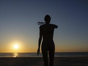 A silhouetted figure in front of a sunset on the beach, sunset in many colours on the beach with a