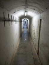 Well-lit narrow tunnel with concrete walls and electrical cables on the side, Heligoland, Germany,