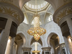 A sublime interior with an ornately decorated ceiling and a magnificent golden chandelier