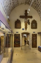 Entrance area with showcases and large wooden cross on wall in vaulted museum Monastery museum in