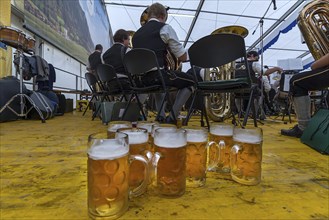 Full beer mugs on the stage of the musicians in a marquee, in the back the band, Bad Hindelang,