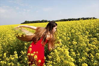 Young woman in a red dress in a rape field