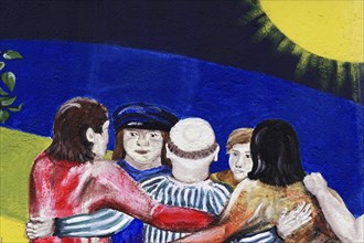 Mural shows a group of people hugging each other under a deep blue sky and a bright sun, Wall