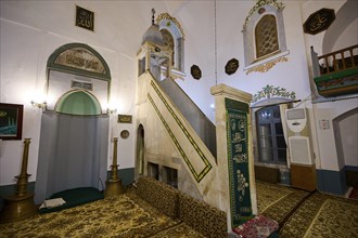 Retzep Pasha Mosque, Prayer room of a mosque with a decorative pulpit, carpets and religious signs,