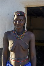 Hakaona woman with traditional kapapo hairstyle and colourful necklaces, portrait, in front of the